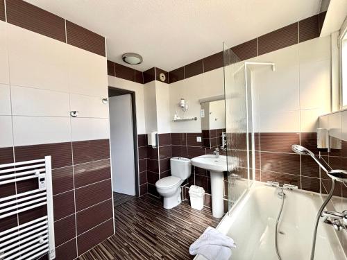 a bathroom with a tub and a toilet and a sink at Hôtel de France Contact-Hôtel in Évian-les-Bains