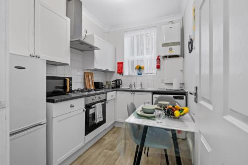 クリーソープスにあるCharming Apartment by the Seaの白いキャビネットとガラスのテーブル付きのキッチン
