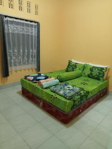 a green bed in a room with a window at Zinzi's All-Inclusive Homestay in Sangyang
