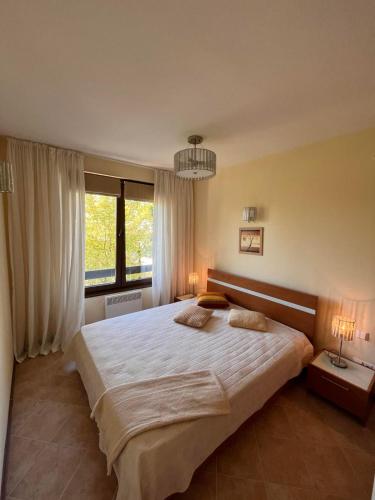 a bedroom with a large bed and a large window at Oasis Resort Apartments in Lozenets