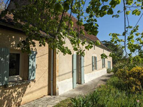 a building with green doors and a street at Maison au calme en Dordogne in Trémolat
