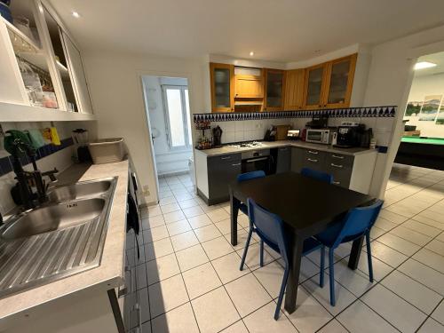 une cuisine avec une table noire et des chaises bleues dans l'établissement Du calme en pleine ville Jacuzzi, à Bordeaux