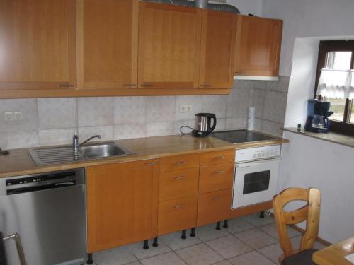 a kitchen with wooden cabinets and a sink and a dishwasher at Ferienhaus Fam. Fuhrer in Hohenaltheim