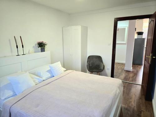 a bedroom with a white bed and a chair at LULU Apartman in Sopron