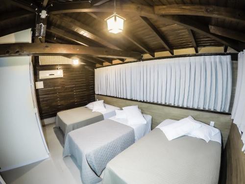a room with three beds in a room at Hotel Guerra - Pousada Montebelo in Jaguaruna