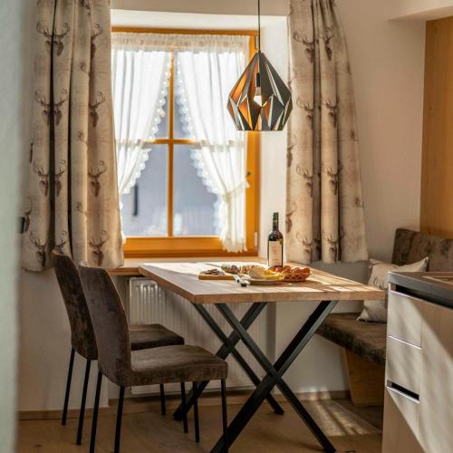 a table with a bottle of wine and chairs in a kitchen at ROSENHOF- Premium & Landhaus Apartments & Wellness & Erlebnisbauernhof in Nauders