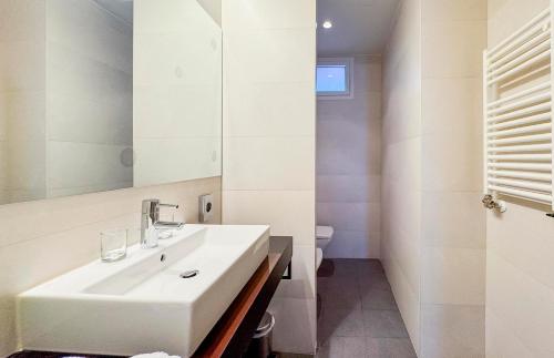 a white bathroom with a sink and a mirror at Hotel Jardines de Uleta Suites in Vitoria-Gasteiz