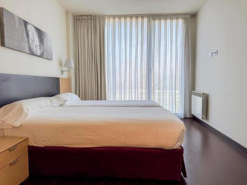 a bedroom with a bed and a large window at Hotel Jardines de Uleta Suites in Vitoria-Gasteiz
