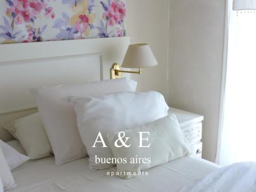 ein Bett mit weißen Kissen und einem Tisch mit einer Lampe in der Unterkunft A & E Buenos Aires in Buenos Aires