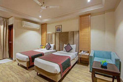 a hotel room with two beds and a blue chair at The Waves Hotel with Free Airport Pickup or Drop in New Delhi