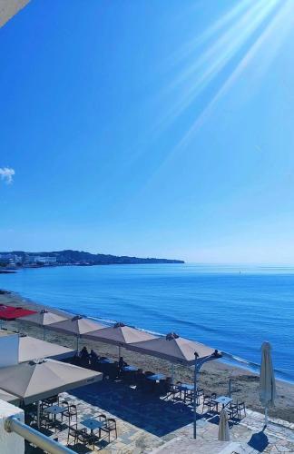 a beach with tables and umbrellas and the ocean at Kyrva Bay Studios in Ierápetra