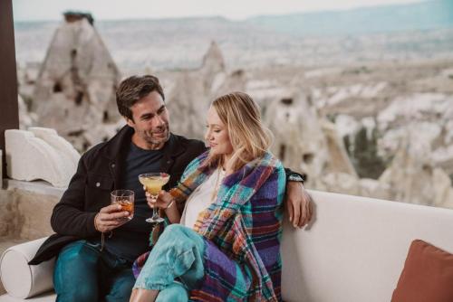 a man and a woman sitting on a couch holding wine glasses at Taskonaklar in Uchisar