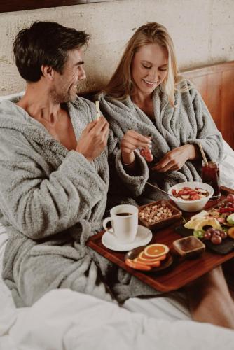 a man and woman sitting in bed with a tray of food at Taskonaklar in Uchisar