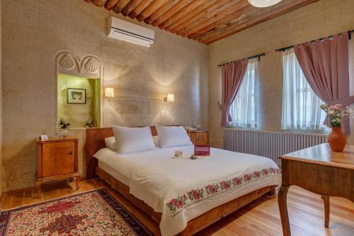 a bedroom with a bed and a table and a mirror at Taskonaklar in Uchisar