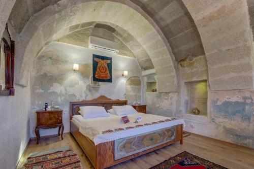 a bedroom with a bed in a stone wall at Taskonaklar in Uchisar
