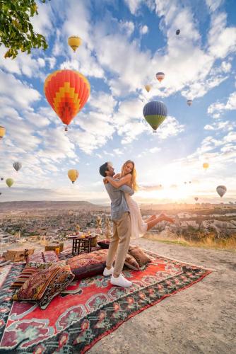 a man and woman standing on top of a hill with hot air balloons at Taskonaklar in Uchisar