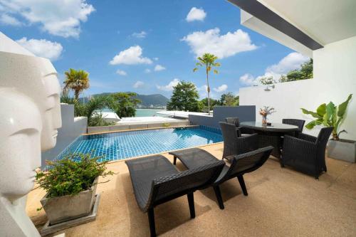 a patio with a pool and chairs and a table at Atika Villas xero oceanfront pool villa in Patong Beach