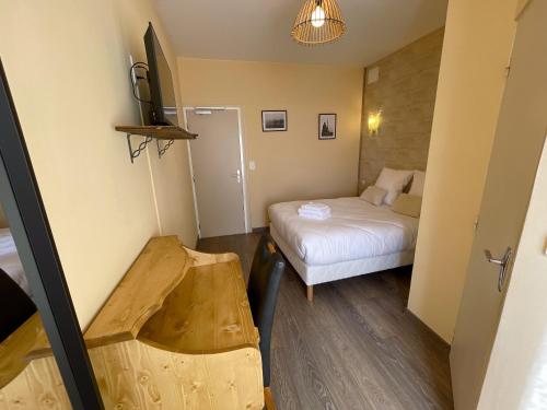 a small room with a bed and a table and a tv at La chaumette in Pannessières