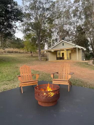 two benches and a fire pit in front of a house at Farm Stay - 2 Bedroom cottage in Murphys Creek
