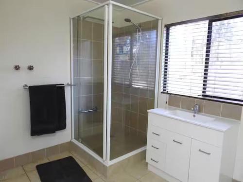 a bathroom with a glass shower and a sink at Farm Stay - 2 Bedroom cottage in Murphys Creek