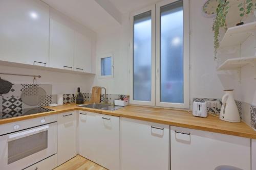 une cuisine avec des placards blancs et une grande fenêtre dans l'établissement Le Madaloca - AC CLIM - WIFI - HYPERCENTRE, à Avignon