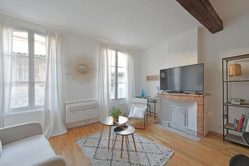 un salon avec un canapé blanc et une télévision dans l'établissement Le Madaloca - AC CLIM - WIFI - HYPERCENTRE, à Avignon