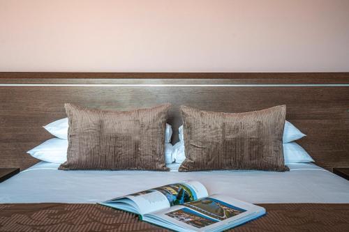 a bed with two pillows and a book on it at Hotel Formula Int. & Puravita SPA in Rosolina