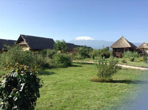 a field with houses and a mountain in the background at AA Lodge Amboseli in Amboseli