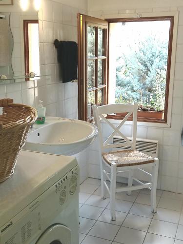 - une salle de bains blanche pourvue d'un lave-linge et d'une chaise dans l'établissement Appartement dans villa provençale, jardins et 3VTT disponibles, à Digne-Les-Bains