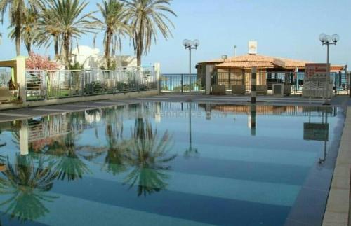 a swimming pool with palm trees and a building at Sea front luxury living apartment in sousse in Sousse