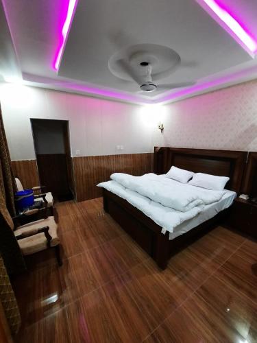 a bedroom with a large bed and a chair at Jan Palace Hotel Kalam Swat in Kalām