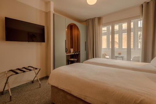 a hotel room with two beds and a television at Maria Rosa Suites in Victoria