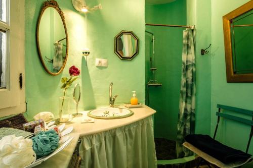 un bagno verde con lavandino e specchio di Casa Petra a Canillas de Aceituno