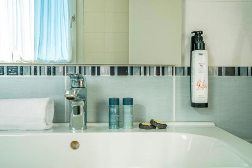 a bathroom with a sink with a bottle of soap and cosmetics at Hotel Formula Int. & Puravita SPA in Rosolina