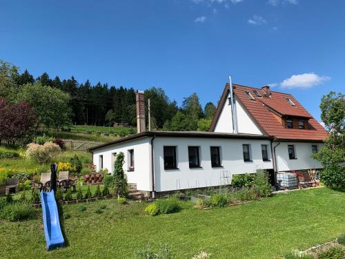 a white house with a slide in the yard at Auf Der Sonnenseite in Zwota