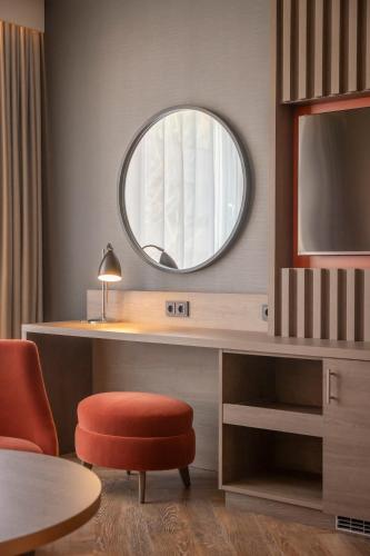 a room with a desk with a round mirror at Clayton Hotel Düsseldorf City Centre in Düsseldorf