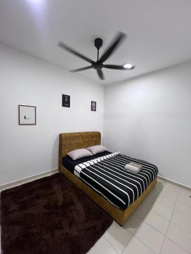 a bed in a room with a ceiling fan at Qmal Homestay in Kampong Jelatang