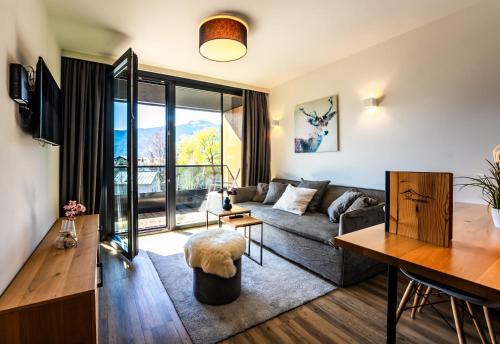 a living room with a couch and a table at Schönblick Residence Apartments - including summer & mobility card in Zell am See