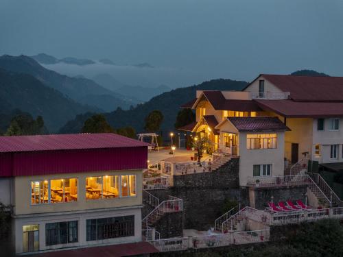 a group of buildings with mountains in the background at Tree of Life Highlands Mussoorie in Mussoorie