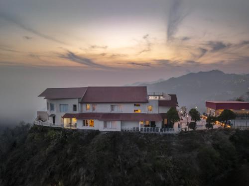 a house on top of a hill with a sunset at Tree of Life Highlands Mussoorie in Mussoorie