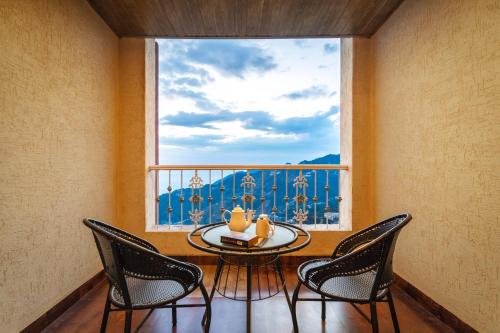 a table and chairs in a room with a window at Tree of Life Highlands Mussoorie in Mussoorie
