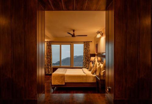 a bedroom with a bed and a large window at Tree of Life Highlands Mussoorie in Mussoorie