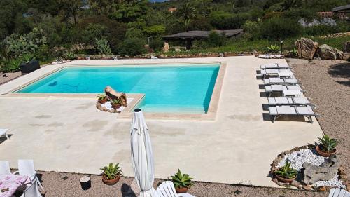 a swimming pool with chairs and an umbrella at Casa Mariposa Porto Rotondo in Rudalza