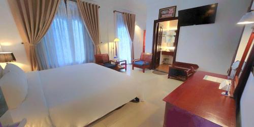 a bedroom with a bed and a desk and a mirror at Victory Hotel in Hue