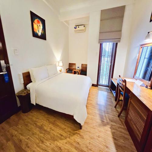 a bedroom with a white bed and a wooden floor at Victory Hotel in Hue