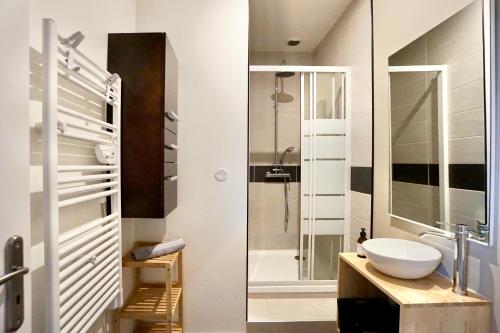 une salle de bain avec un lavabo et une douche en verre dans l'établissement Le Duplex - centre ville, à Concarneau