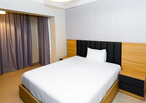 1 dormitorio con cama blanca y cabecero negro en Luxury 3BR Apartment Pool View, en El Cairo