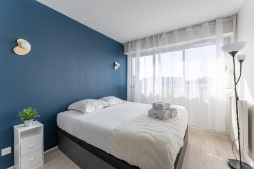 une chambre avec un grand lit avec un mur bleu dans l'établissement Asirem - Pied de métro dans le 7ème, à Lyon