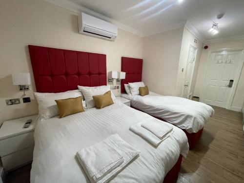 a bedroom with two beds with red headboards at Crompton Guest House in Hounslow