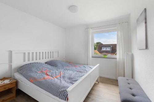 Una habitación blanca con una cama y una ventana en Wiebke, en Büsum